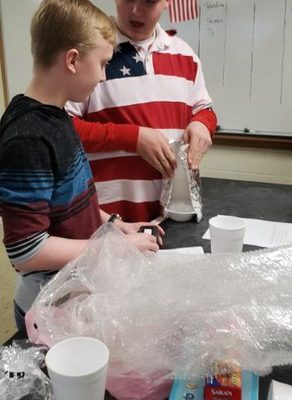 Students discover if a coat keeps a snowman from melting